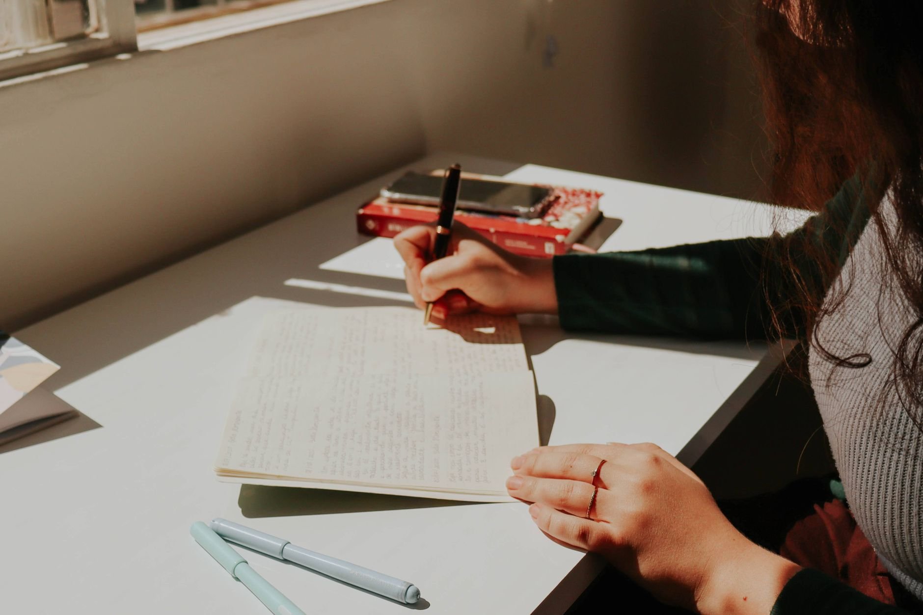 Woman writing in a journal by warm sunlit window